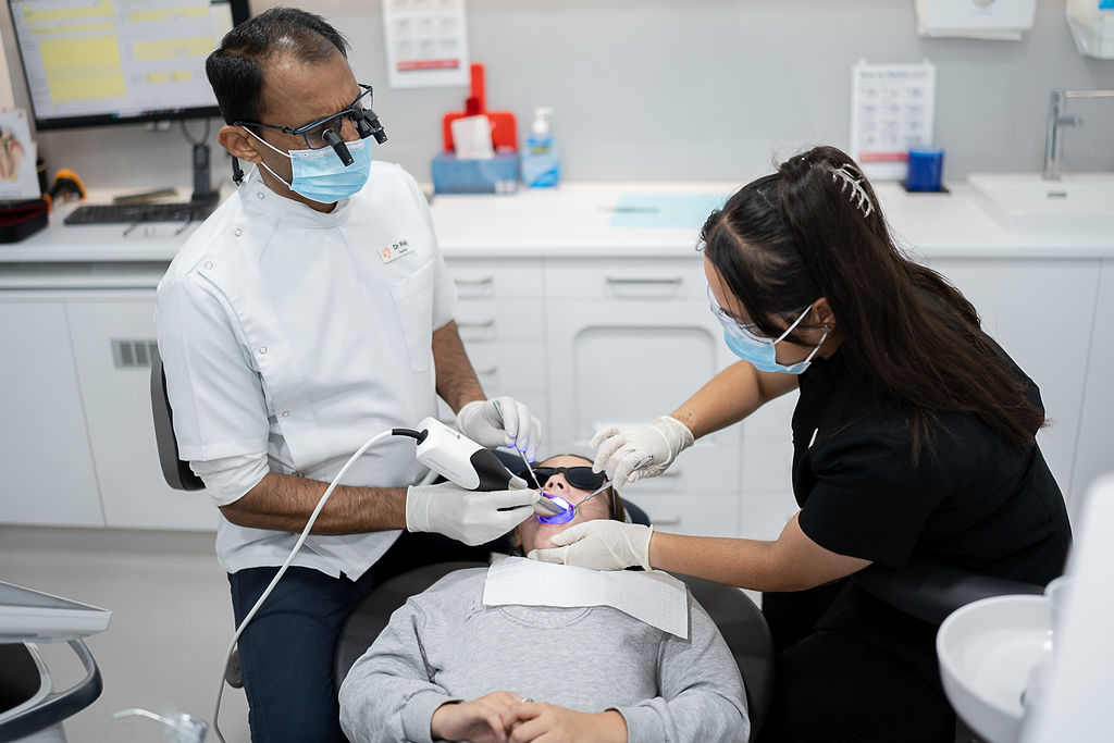 Dentist and dental assistant performing a composite filling procedure on a patient at Dentist at Underwood