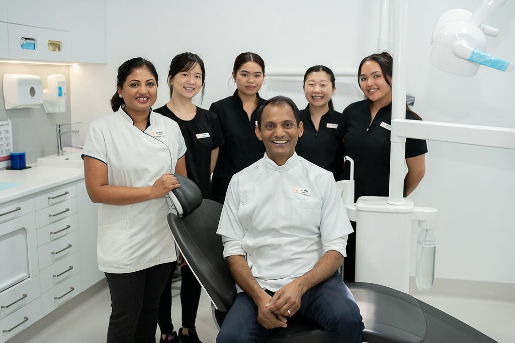 Dentist at Underwood team posing together around the dental chair at their Underwood clinic