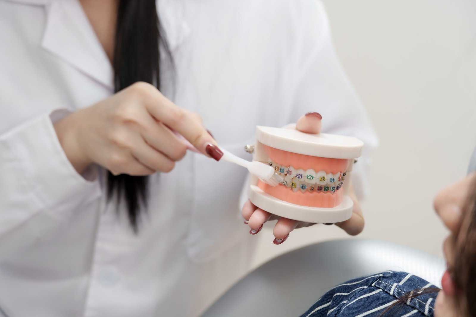 A dentist at Underwood using a dental model and toothbrush to demonstrate proper cleaning techniques for braces.