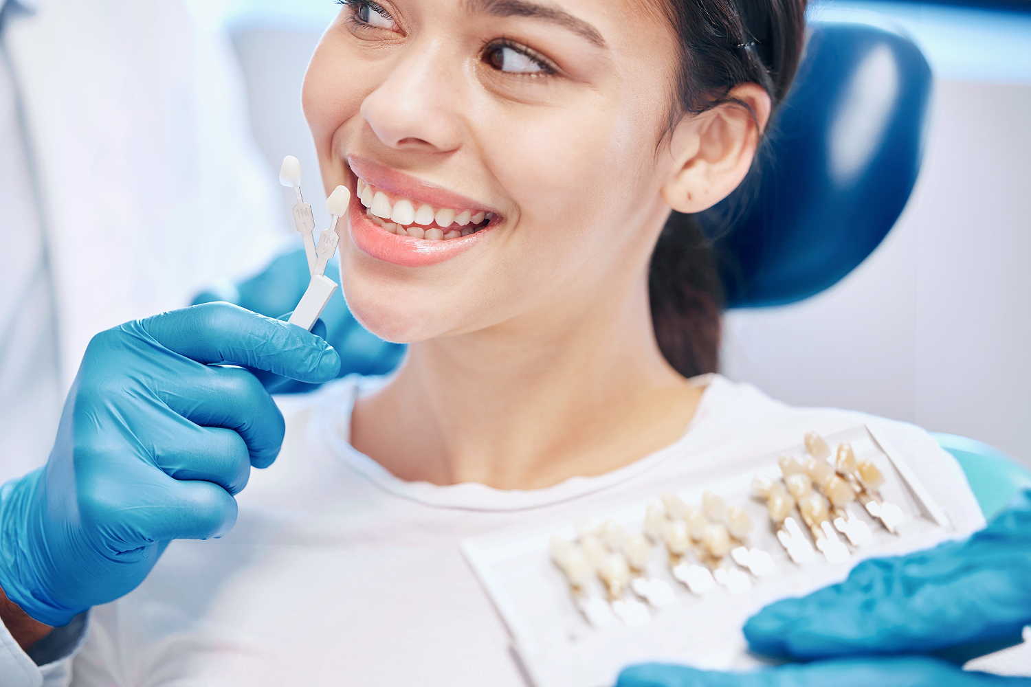 Dentist using a professional tooth shade guide to match the natural colour of a smiling patient's teeth